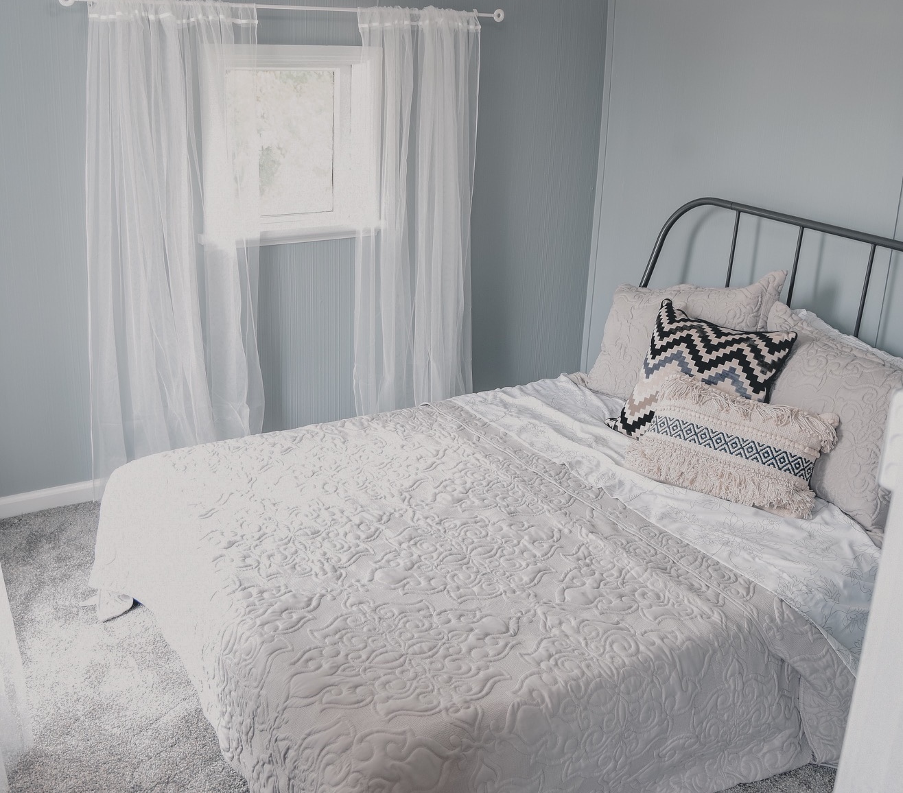 A cozy bedroom in the Bridal House with a metal-frame bed and soft bedding