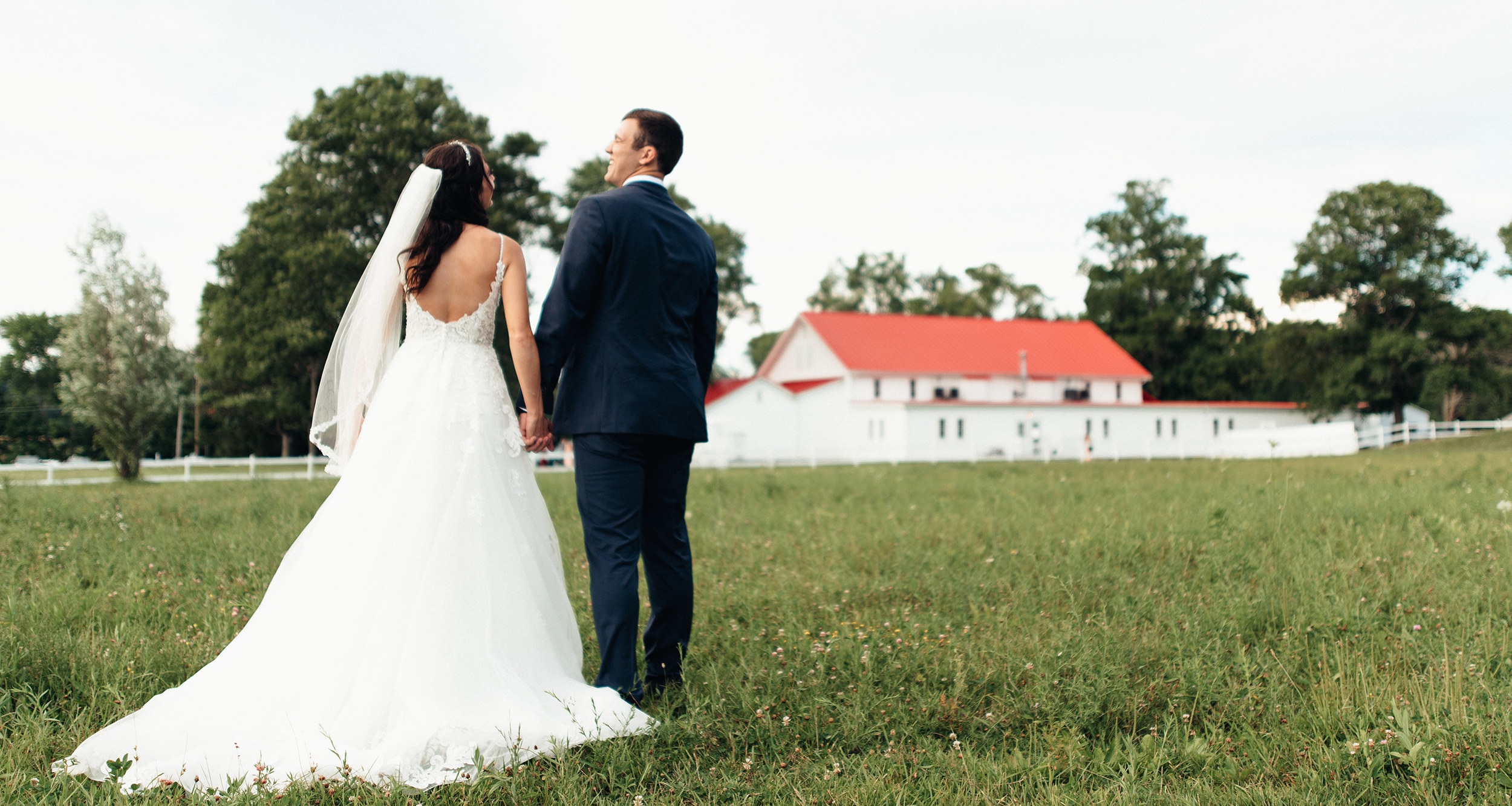 bride and groom entering red barn